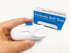 A 3D printed SLA prototype of the blood sampling device in somebody's hand with packaging mock up in the background