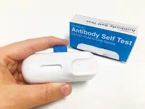 A 3D printed SLA prototype of the blood sampling device in somebody's hand with packaging mock up in the background