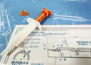 Plastic syringe prototype on top of a syringe patent and engineering drawing for the pharma industry