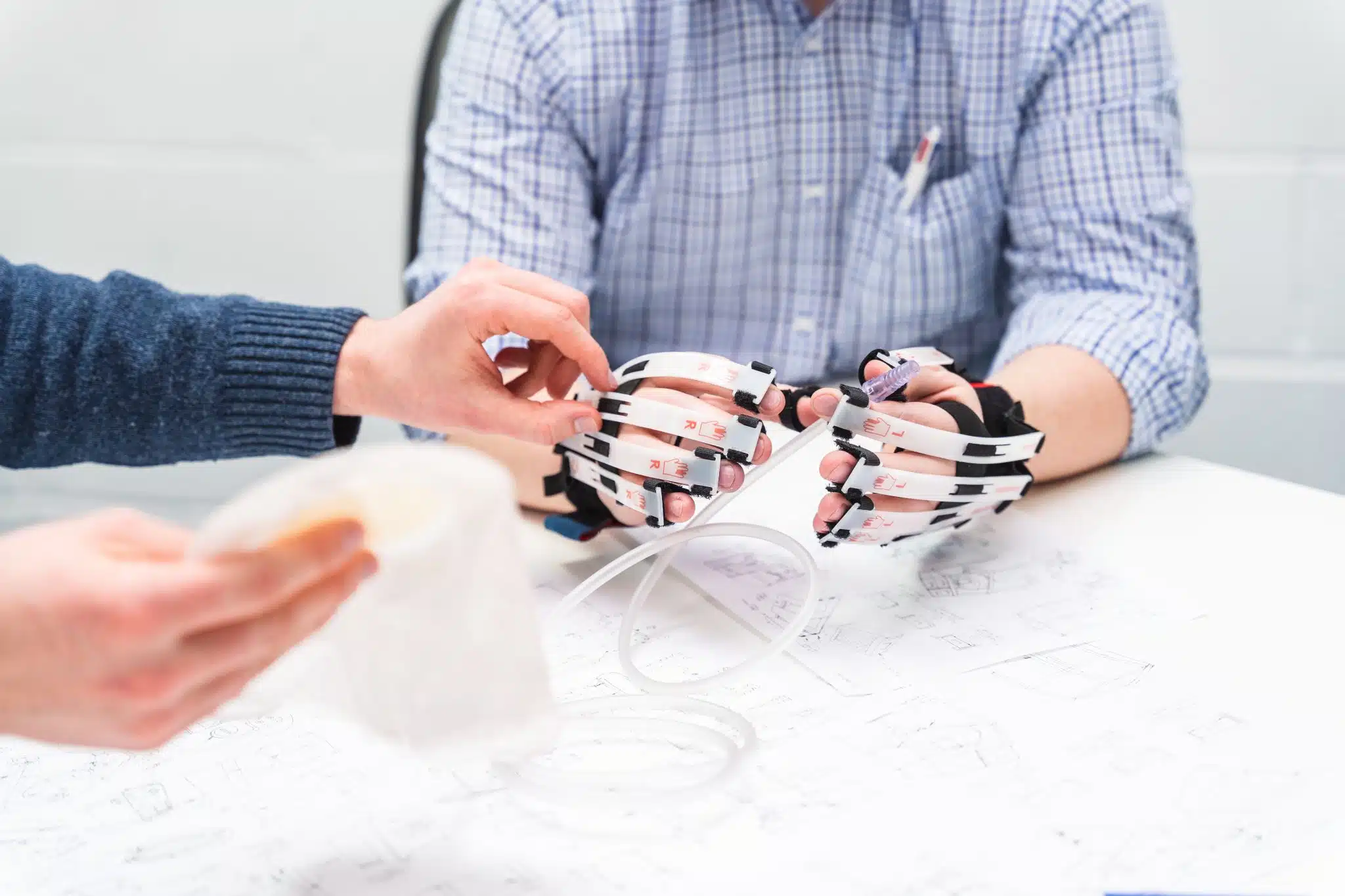 Image showing human factors designers using simulation gloves to test a medical device as part of the human factors engineering process for medical device development services