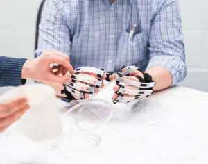 Image showing human factors designers using simulation gloves to test a medical device as part of the human factors engineering process for medical device development services